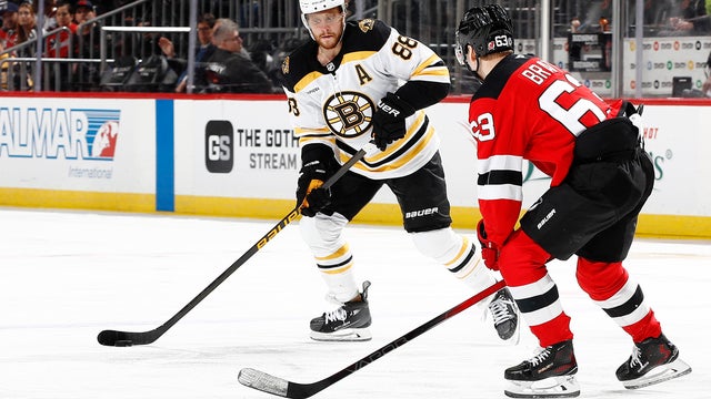David Pastrnak #88 of the Boston Bruins controls the puck as Jesper Bratt #63 of the New Jersey Devils defends during the third period at Prudential Center on April 08, 2025 in Newark, New Jersey. 